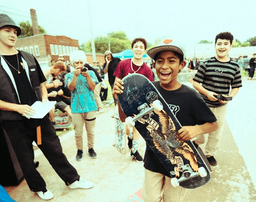 A young Omaha skateboarder smiles at the camera.