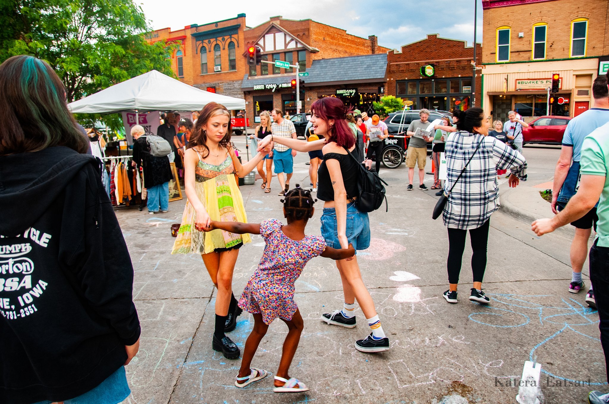Two adults and a child dancing in the Benson Creative District at a First Friday event.