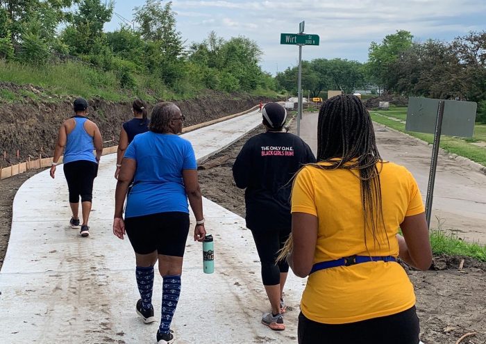 Five women walk on the newly completed North Omaha Trail. Their backs are to the camera and they are wearing athletic clothes.
